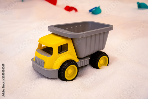 фотографія Yellow toy dump truck on soft white play surface