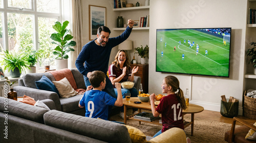 Enthusiastic Family with Face Paint Cheering and Celebrating Goal While Watching Soccer Match on Television in Bright Modern Living Room