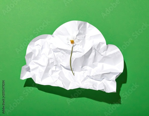 A crumpled white paper cloud with a delicate flower against a vibrant green background