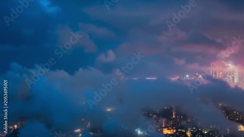 Dramatic aerial view of a modern city skyline peeking through dark blue night clouds