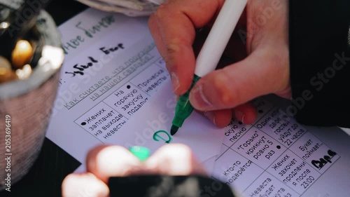 A man writes with a felt-tip pen on a white sheet. Close-up shot of the hand