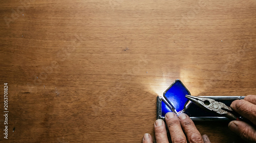 Hand placing blue stained glass isolated on a clean white background