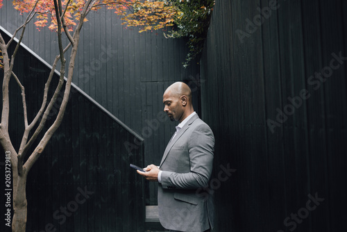 Man in Suit Checking Phone in Urban Setting