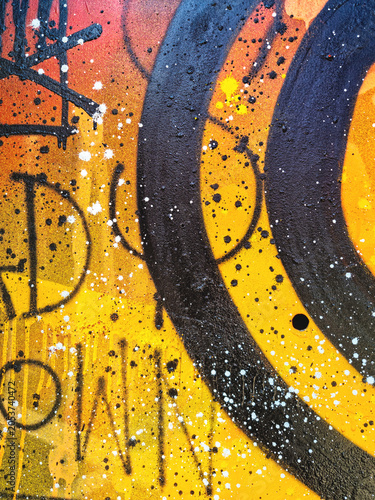 Abstract urban graffiti art in orange, black, yellow with white splatter detail. 90s, street style, grungy, paint texture. Poster, background, wall art, urban culture, creative banner.