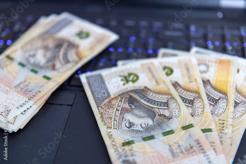 Banknoty 200 złotych na klawiaturze laptopa — praca zdalna, zarobki online, finanse