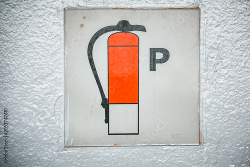 Foto Close-up of a photoluminescent shipboard fire fighting equipment symbol indicating a powder extinguisher, mounted on a textured white bulk head wall