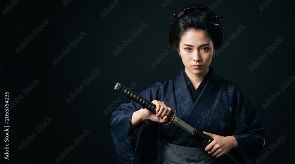 Fototapeta premium 漆黒の背景に凛と際立つ武士道スピリット。伝統的な羽織袴を纏った日本人女性の真剣な眼差しと、力強く手に持った日本刀がドラマチックな陰影で緊迫感を魅せるクローズアップポートレート