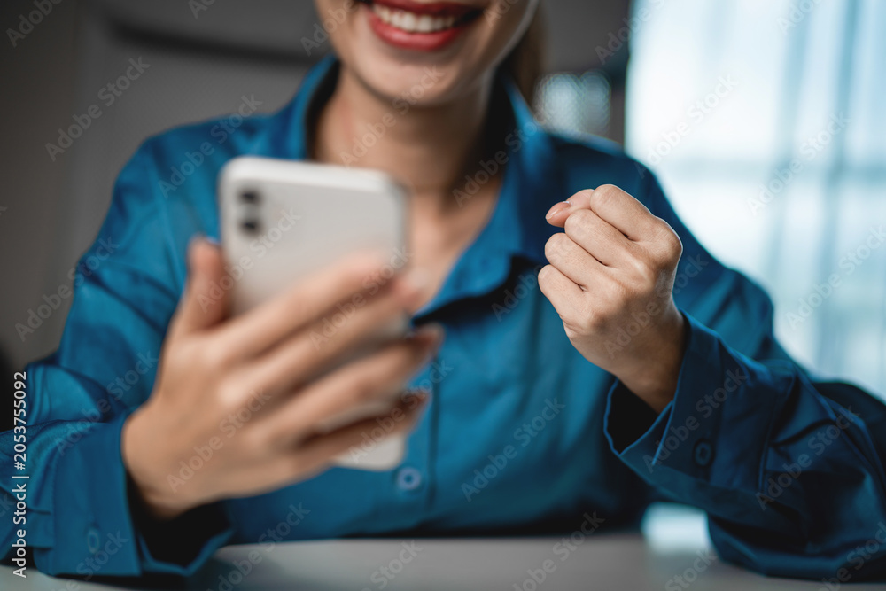 Fototapeta premium Happy Woman Celebrating Good News on Smartphone at Home Office. Success notification, financial achievement, happiness, digital lifestyle