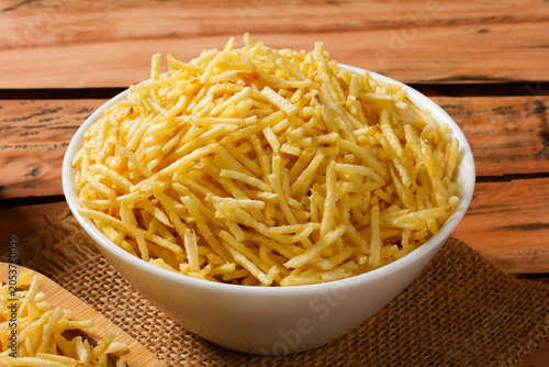 Portion of golden potato sticks inside a white ceramic bowl with burlap fabric at the bottom