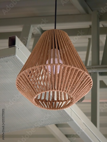 Decorative hanging pendant lamp featuring a woven rope shade suspended from a modern industrial ceiling fixture