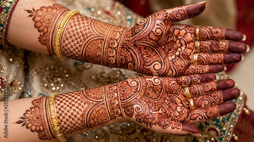 Hands with colorful henna tattoos holding money