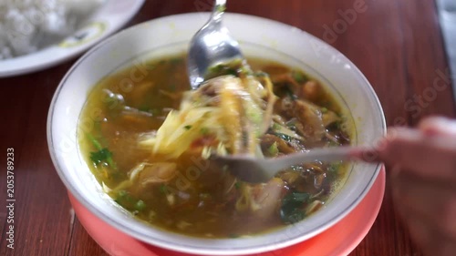 A warm and delicious bowl of traditional Indonesian chicken soup (Soto Ayam) with shredded chicken, cabbage, and fresh green onion topping.