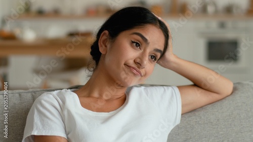 Photos Close up sad frustrated Indian Arabian woman home couch pensive thoughtful upset