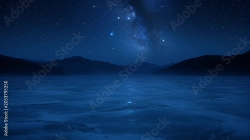 Nighttime landscape with lake reflecting starry sky and distant mountains