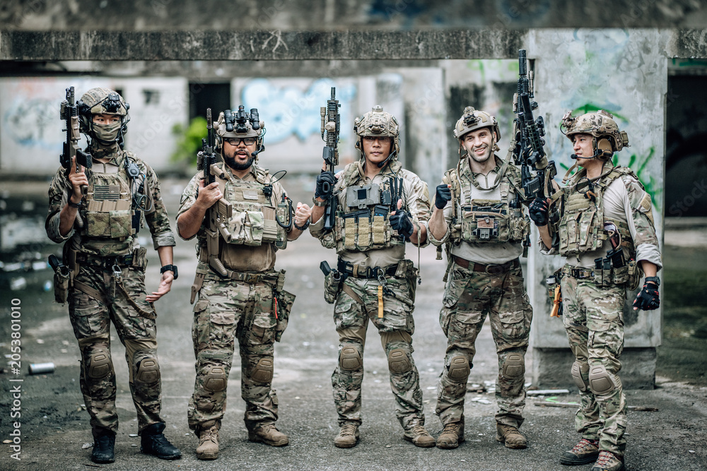Fototapeta premium Tactical team celebrates mission success raising helmets and fists together in abandoned building