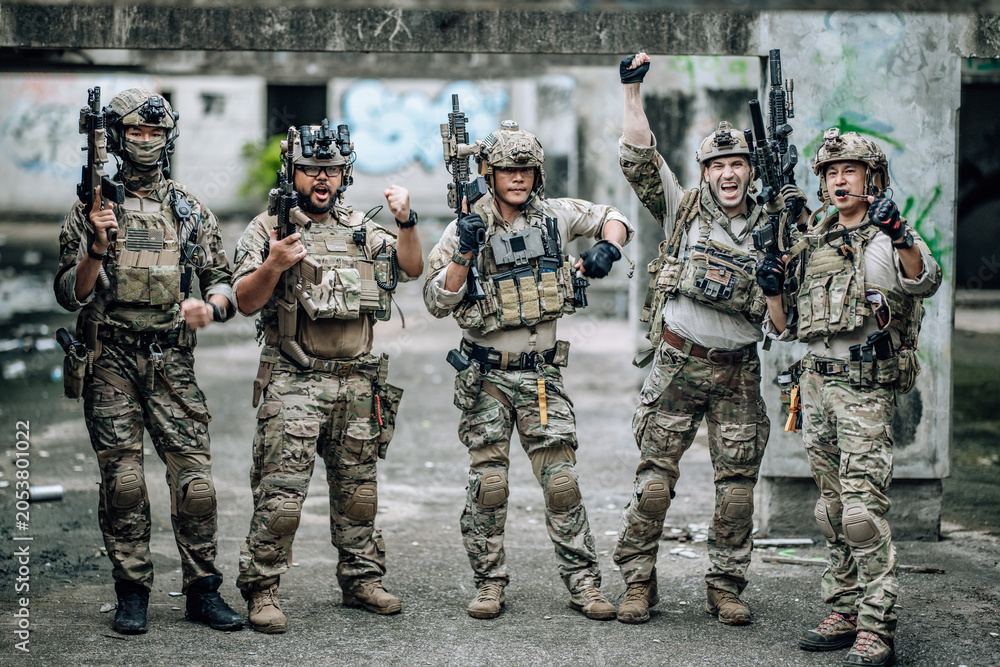 Fototapeta premium Tactical team celebrates mission success raising helmets and fists together in abandoned building