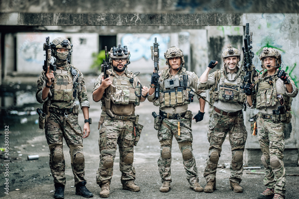 Fototapeta premium Tactical team celebrates mission success raising helmets and fists together in abandoned building