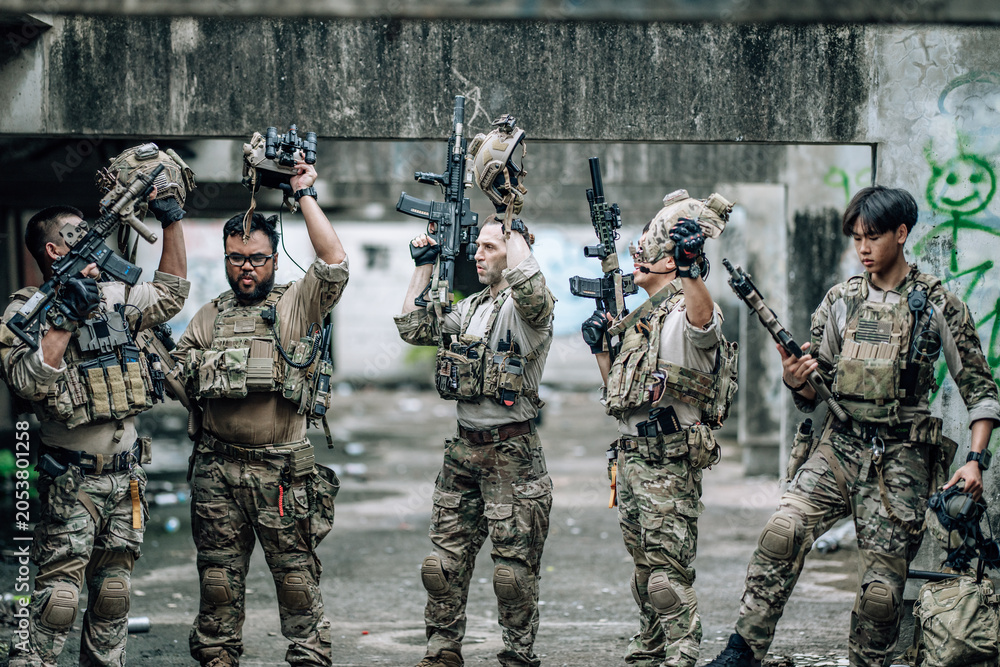 Fototapeta premium Tactical team celebrates mission success raising helmets and fists together in abandoned building