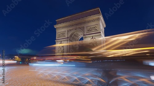 Cars blur in front of camera at night;  time lapse shot of Arc de Triomphe Paris, France. 
