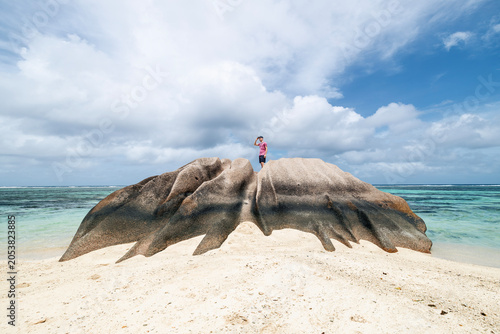 Obraz na plátne Tourist standing on top of granite rock in Seychelles and looking around at horizon