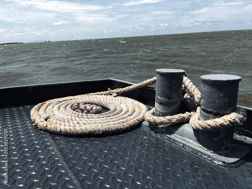 coiled rope on a boat deck with metal bollards, ocean waves, and blue sky in the background, capturing a nautical scene of travel, transportation, and maritime life sea ship wave summer anchor