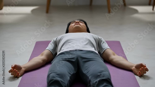 Person relaxing on yoga mat inside preparing for exercise meditation