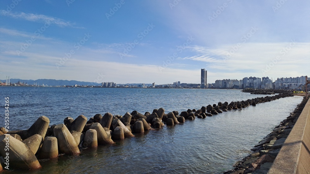 Obraz premium tetrapod breakwater and coastal city skyline under a clear blue sky