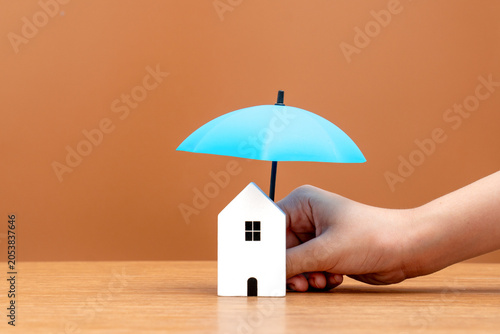 Konstfotografi A blue umbrella positioned directly over a small white house model