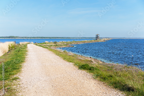 Scenic gravel pathway leading to a wooden bird-watching tower on Lake Liepaja, Latvia