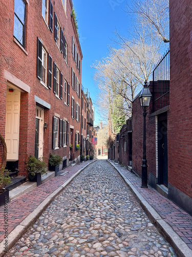 Acorn Street, a historic cobblestone lane lined with red brick row houses, showcases the timeless charm of Boston's Beacon Hill neighborhood.