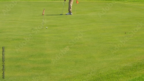 Putting in golf, on the golf course green.
