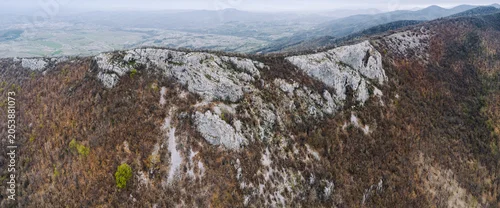 Panel kuchenny z motywem Panorama showing a rugged mountain ridge with exposed rocky outcrops overlooking a a vast valley and distant hills
