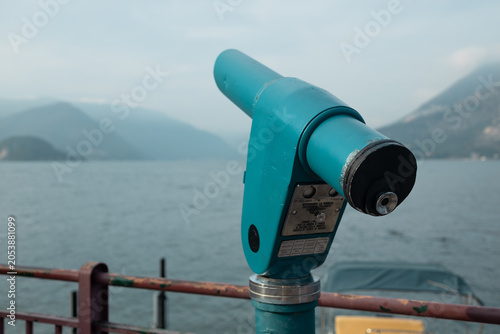 Metal viewing binoculars installed on a promenade for tourists to enjoy scenic panorama and nature landscape during vacation trip.