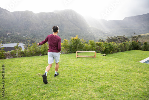 Low wooden bench sitting on manicured lawn near pool edge with mountains rising under sun rays