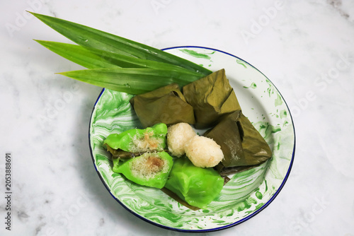 Traditional Indonesian Mendut cake with pandan leaves. Javanese sweet snack is made from glutinous rice flour, coconut and palm sugar, then wrapped in banana leaves and steamed. white backround.
