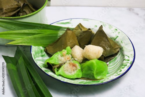 Traditional Indonesian Mendut cake with pandan leaves. Javanese sweet snack is made from glutinous rice flour, coconut and palm sugar, then wrapped in banana leaves and steamed. white backround.