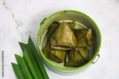 Traditional Indonesian Mendut cake with pandan leaves. Javanese sweet snack is made from glutinous rice flour, coconut and palm sugar, then wrapped in banana leaves and steamed. white backround.