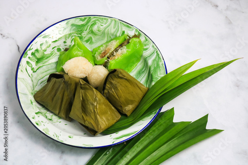 Traditional Indonesian Mendut cake with pandan leaves. Javanese sweet snack is made from glutinous rice flour, coconut and palm sugar, then wrapped in banana leaves and steamed. white backround.