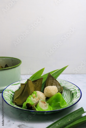 Traditional Indonesian Mendut cake with pandan leaves. Javanese sweet snack is made from glutinous rice flour, coconut and palm sugar, then wrapped in banana leaves and steamed. white backround.