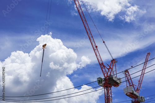 Tablou pe pânză Construction workers operating on a modern building construction site with tower crane under blue sky