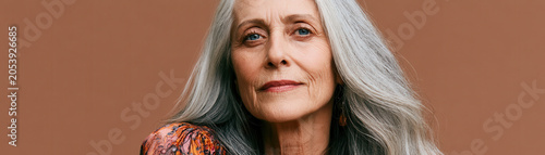 Elderly woman senior woman gray hair long hair wrinkle face portrait studio beauty mature woman serene elderly woman calm expression and gentle smile on brown background