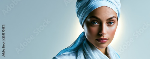 Serene woman portrait blue headscarf confident gaze soft lighting studio background modern fashion cultural style modest clothing calm expression beauty
