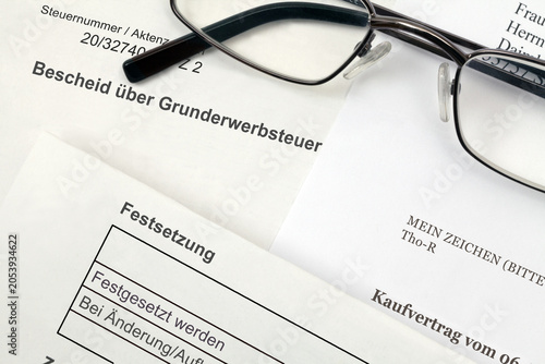Bescheid über Grunderwerbsteuer und notarieller Kaufvertrag mit Lesebrille