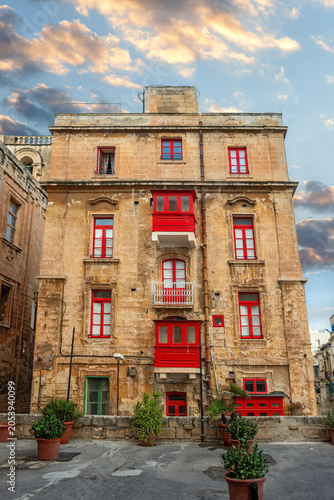Street view of famous building with maltese red balconies and windows at downtown of Valletta. Malta