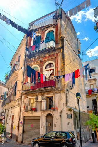 Clothes are dried on ropes outside between buildings in street at historical district of Catania. Sicily, Italy