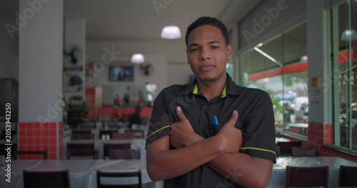 Foto Latino restaurant employee standing with arms crossed in dining area, confident