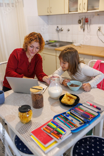Mother teaching daughter to use laptop computer