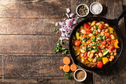 Healthy vegetable and bean stew with fresh herbs and spices in a cast iron skillet