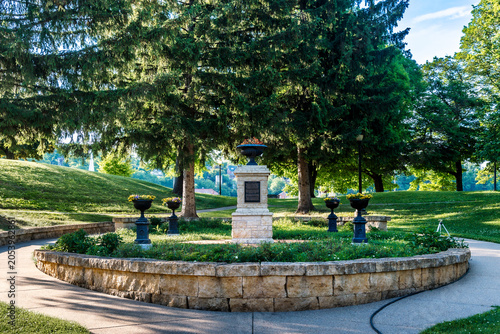 Canvas Print Historic stone memorial surrounded by landscaped gardens and towering evergreen