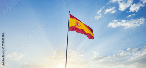 Flag of Spain waving at the top of a post with a bottom of sunny blue sky